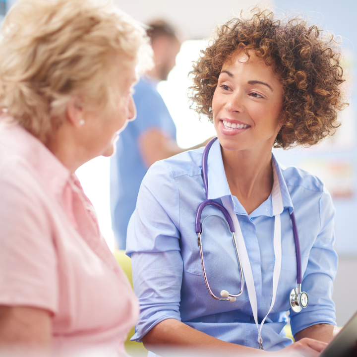 A young female doctor speaking with an older patient