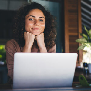 A woman smiling in front of her laptop