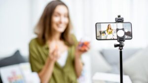 A woman recording a video with her phone on a tripod