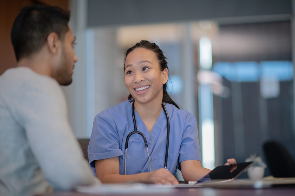 An attractive nurse discusses the recent results with another doctor during a consultation at the hospital. She is slightly smiling.