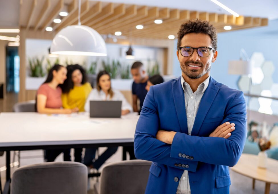 Portrait of a business man working at a coworking office and looking at the camera while a group works at the background