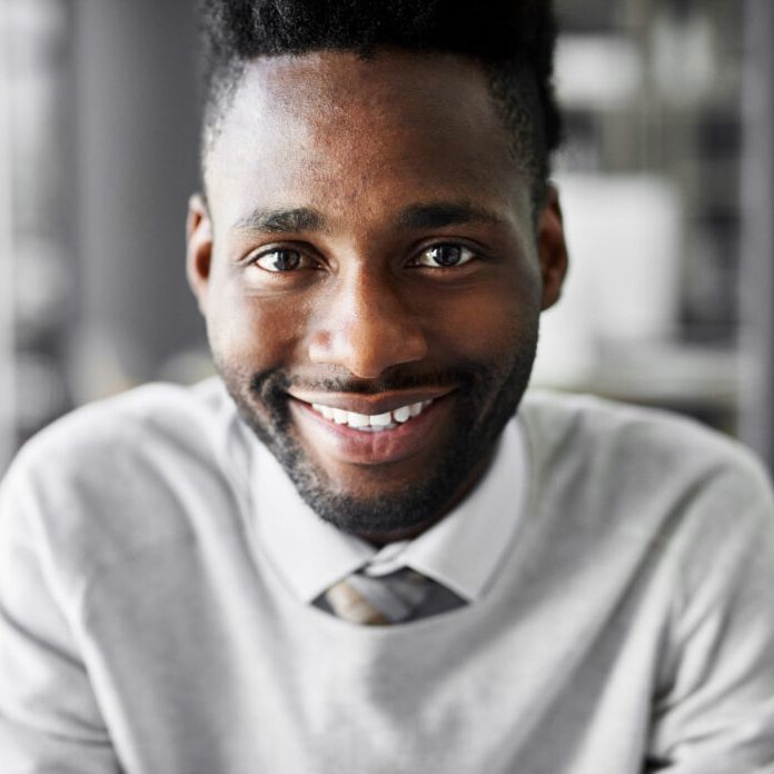 Portrait of a smiling young businessman sitting at a desk in an office